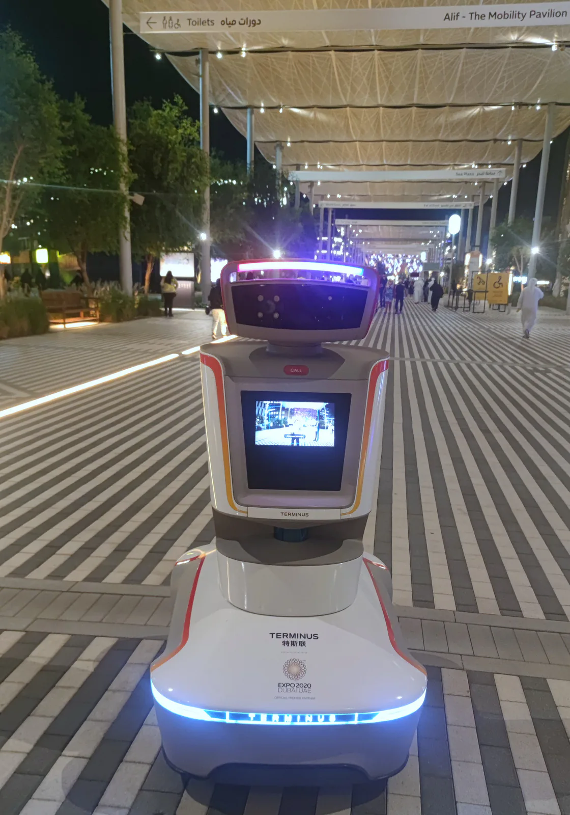 Terminus service robot with the Expo 2020 Dubai logo on a lit walkway, with a sign to Alif, the Mobility Pavilion