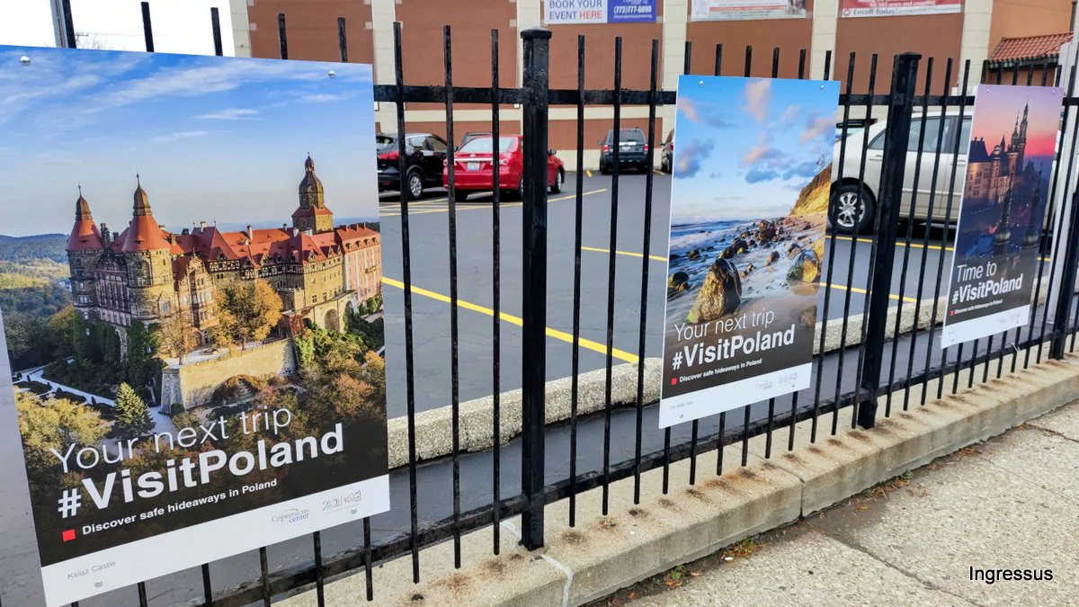 Close-up of #VisitPoland posters of Książ Castle and a rocky seashore on the Copernicus Foundation fence in Chicago