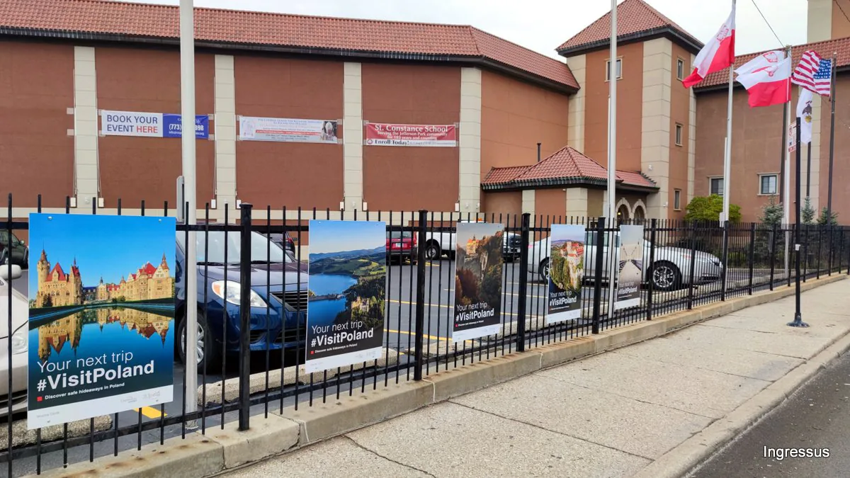 #VisitPoland posters of Moszna Castle, a lake and other Polish sights on the fence of the Copernicus Foundation building, with Polish and U.S. flags