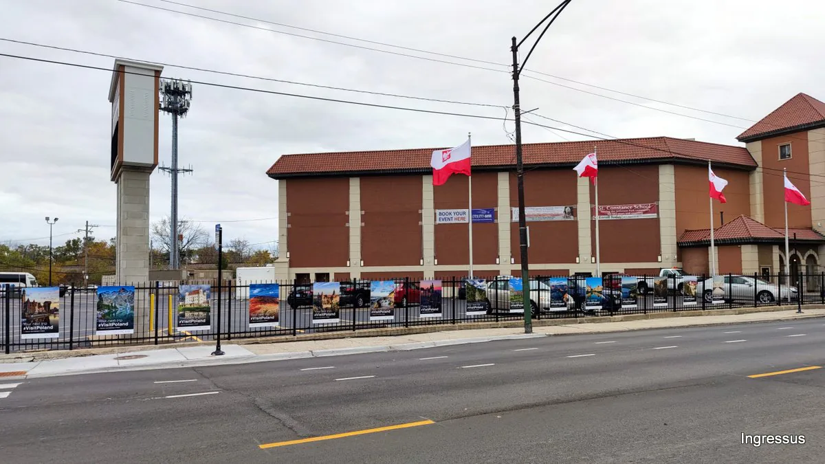 Street view of the Copernicus Foundation building in Chicago with Polish flags and the #VisitPoland poster exhibition along its fence