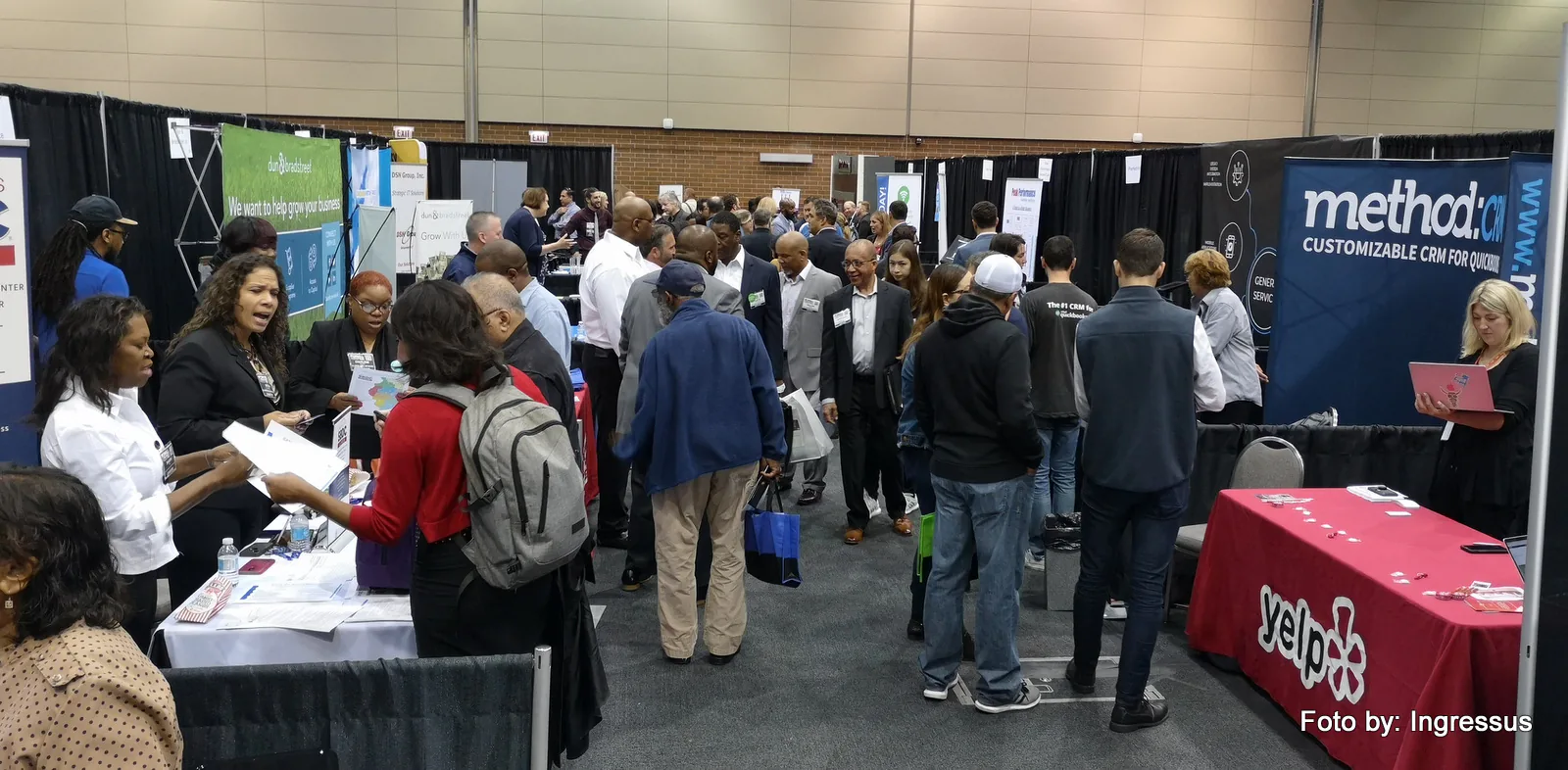 Attendees visiting exhibitor booths, including Method CRM and Yelp, in the crowded exhibitor hall of Small Business Expo 2019
