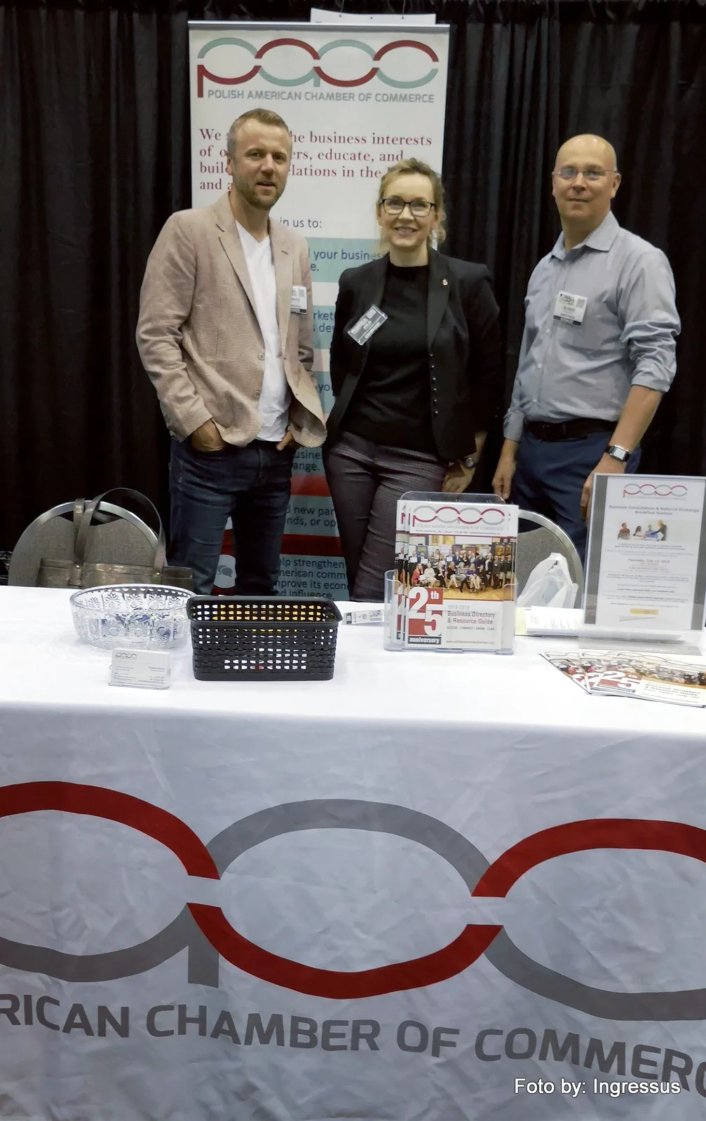 Three people at the Polish American Chamber of Commerce booth with its 25th anniversary business directory, Small Business Expo 2019
