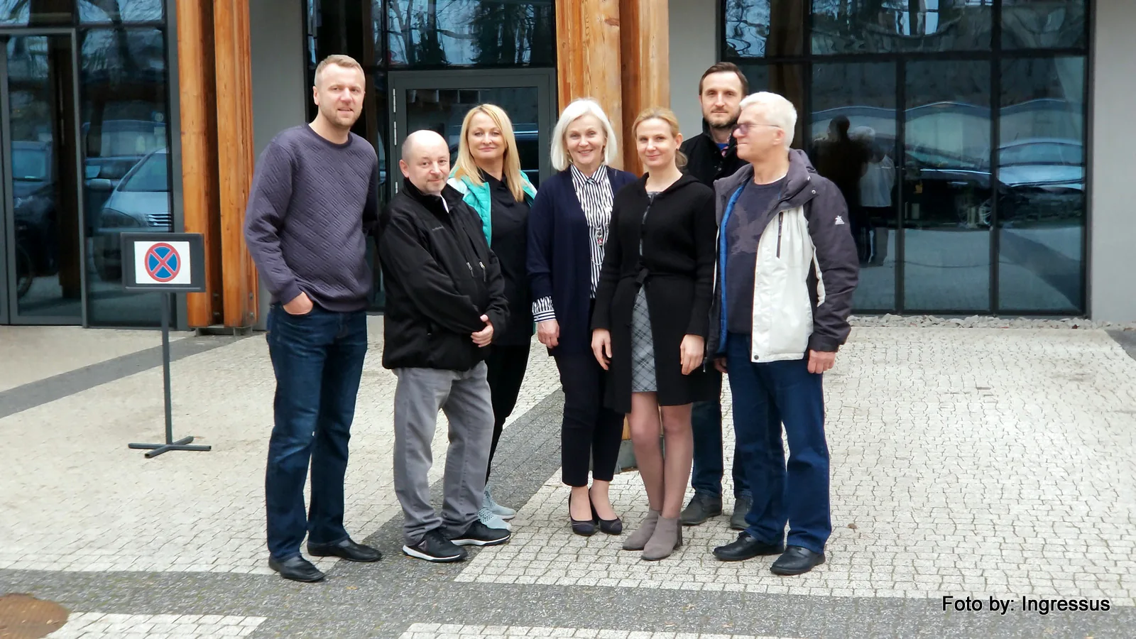 Study tour participants posing in front of a modern wood and glass building in Poland, March 2019