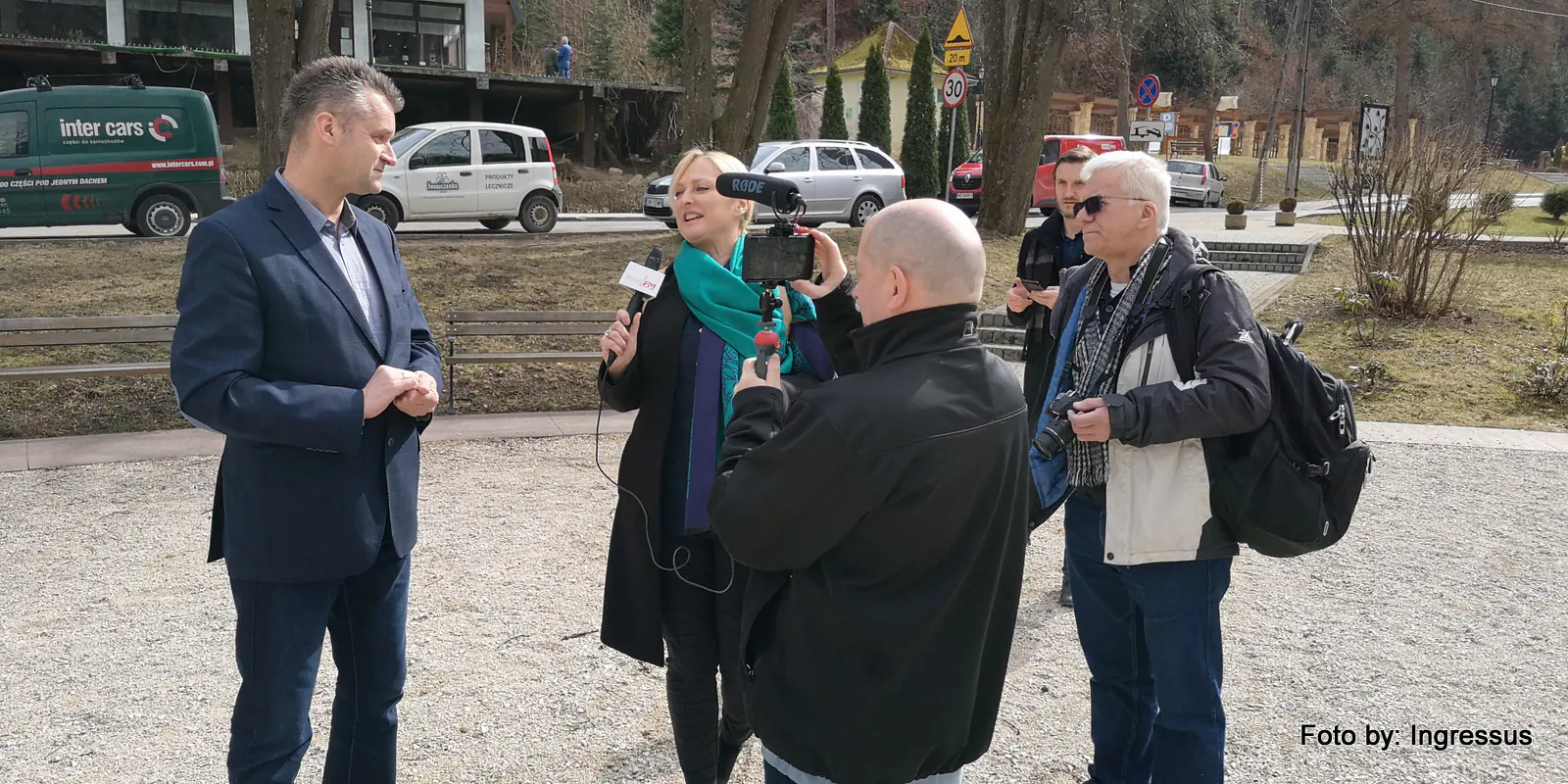 Journalist with a microphone interviewing a man while a camera operator films, in a Polish spa town during the 2019 study tour