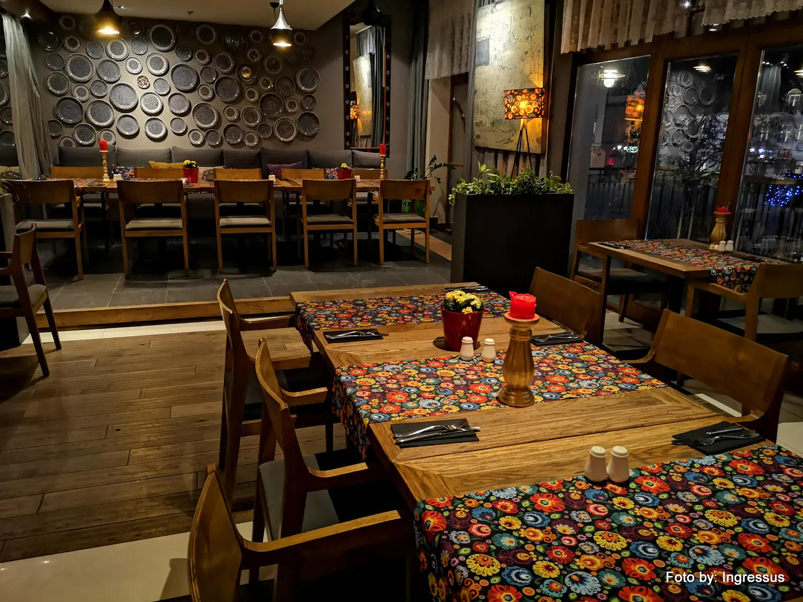 Restaurant interior with wooden tables, colorful Polish folk-pattern table runners and a wall of decorative plates