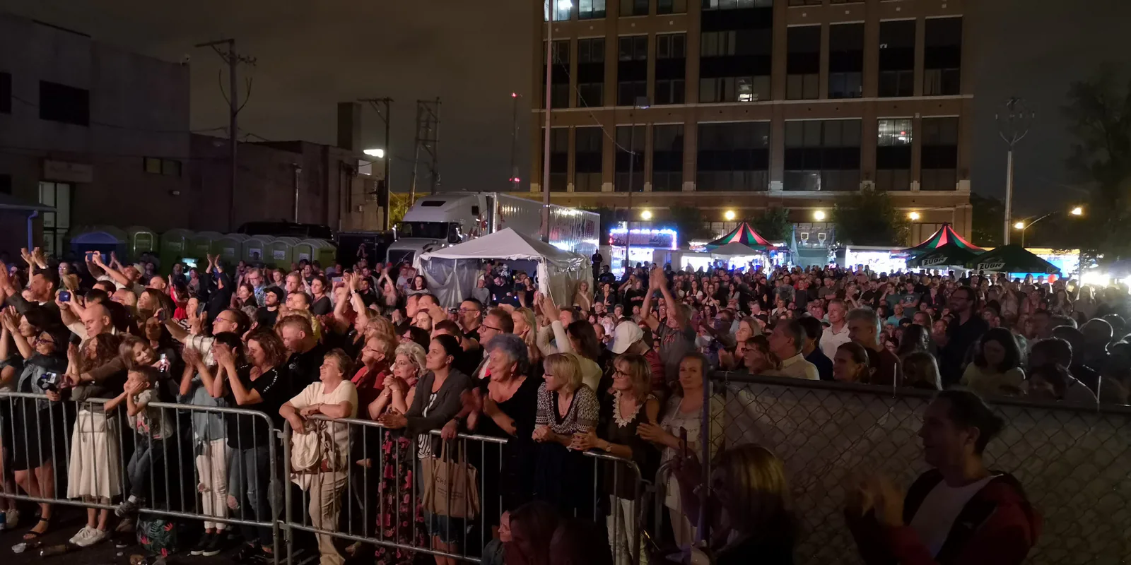 Evening crowd of fans behind barriers, many raising their phones, watching a concert at Taste of Polonia in Chicago