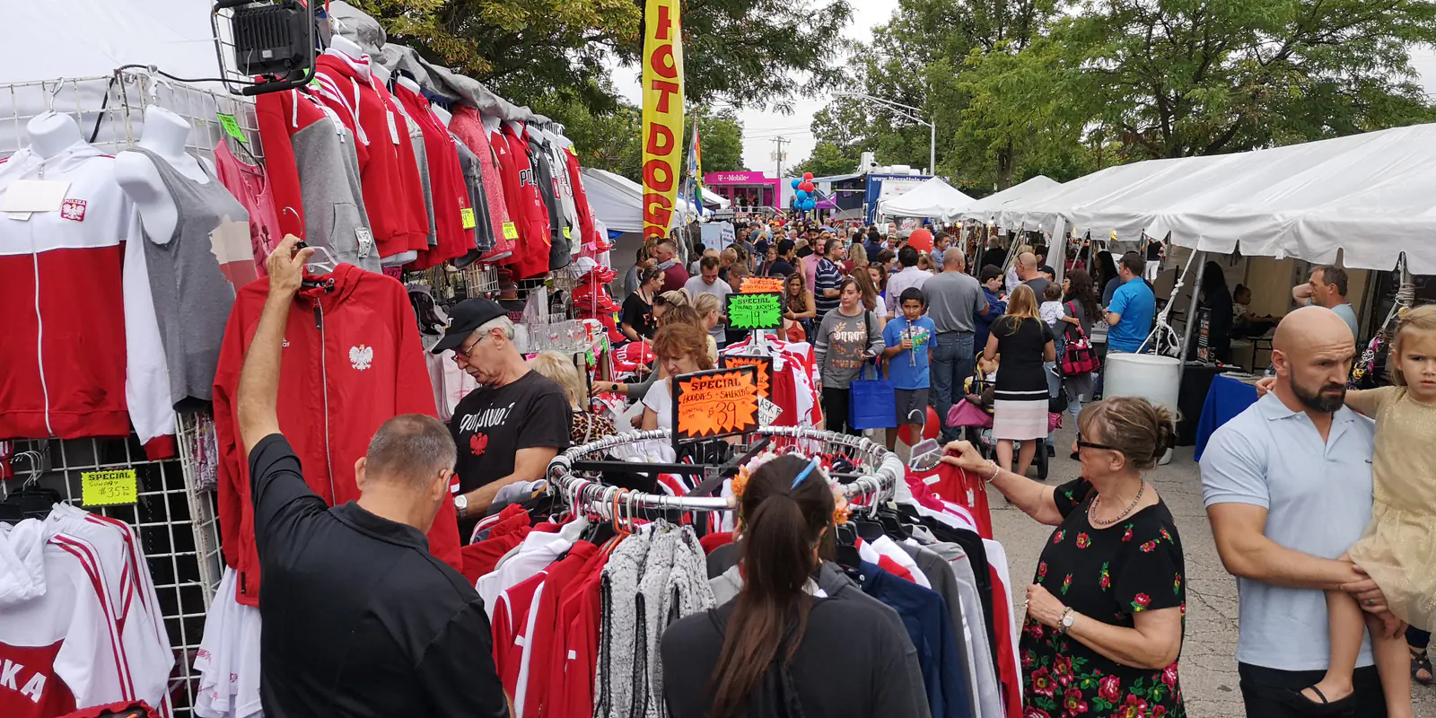 Crowded festival aisle with stalls selling red and white Poland sweatshirts and fan apparel at Taste of Polonia 2019
