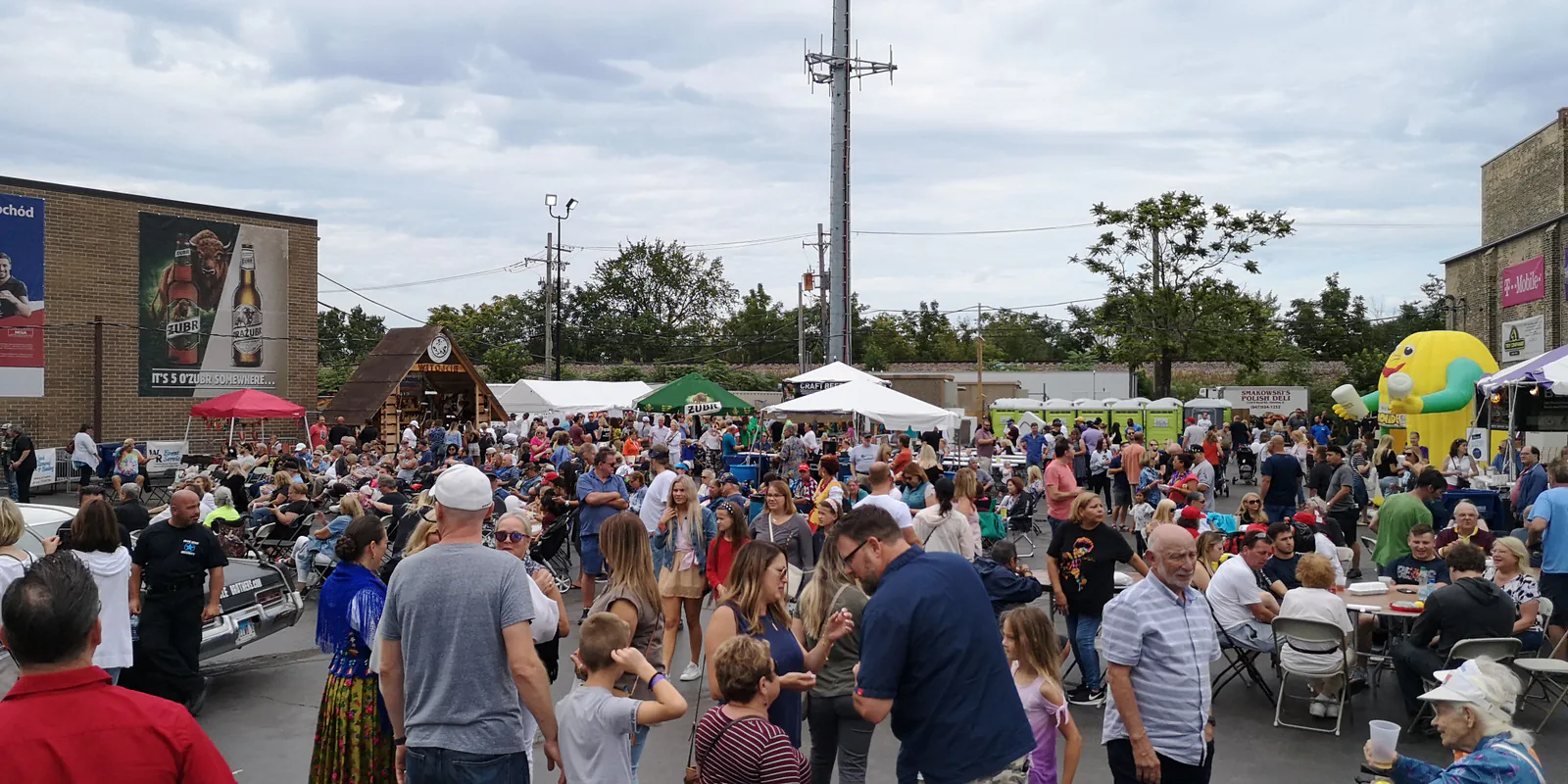 Crowd of visitors among food tents and tables at the Taste of Polonia Festival in Chicago, with a Żubr beer billboard on a wall
