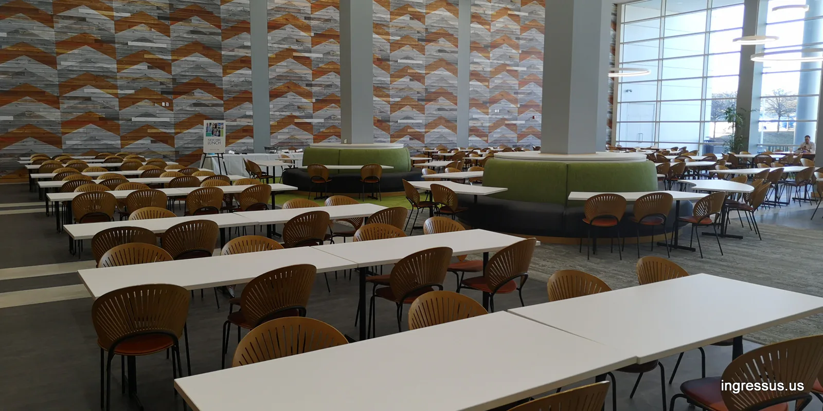 Spacious cafeteria with long tables, booth seating and a patterned wood wall at United Wholesale Mortgage headquarters in Pontiac