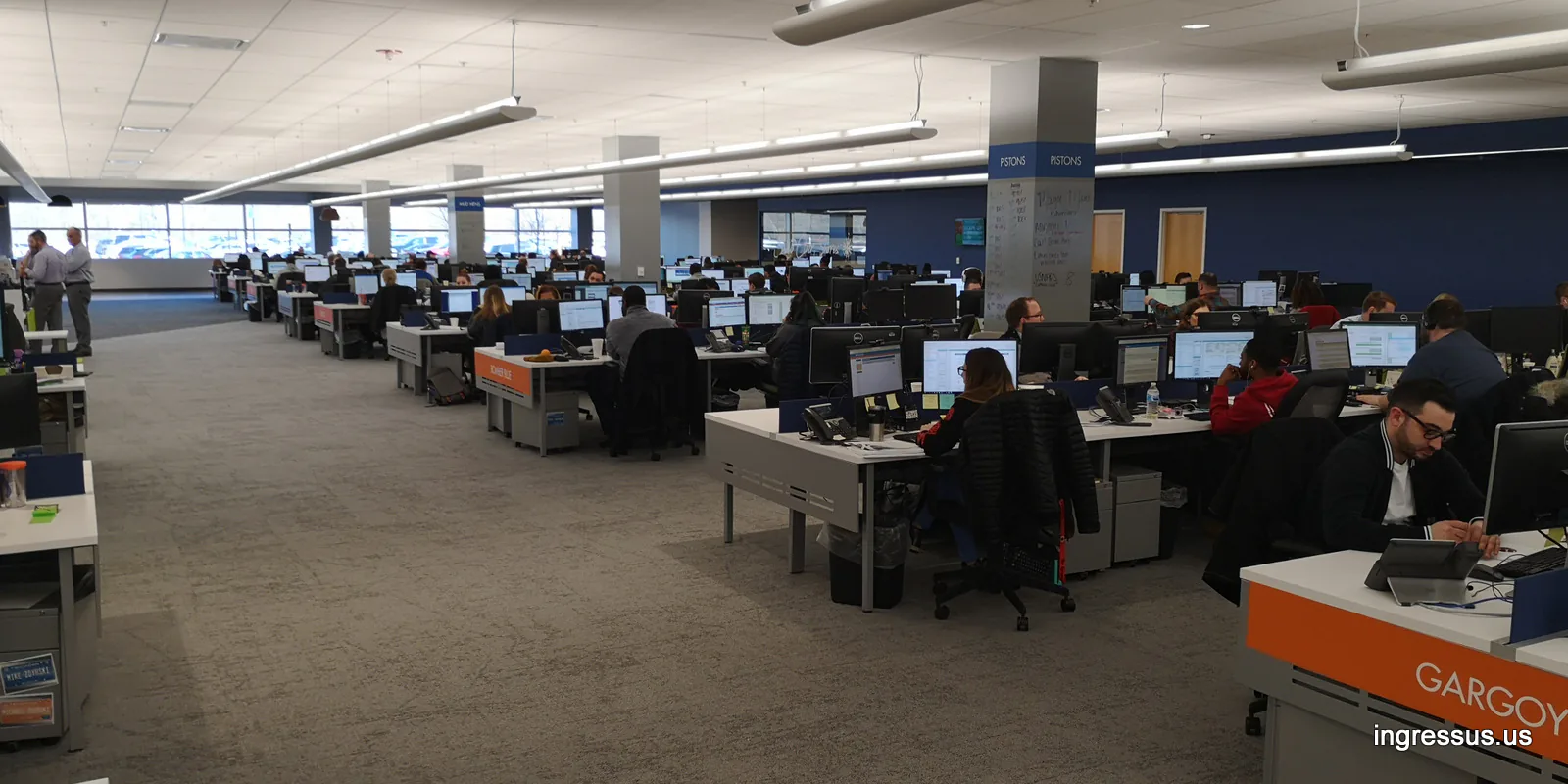 Open-plan office floor with rows of workstations and team signs at United Wholesale Mortgage headquarters in Pontiac